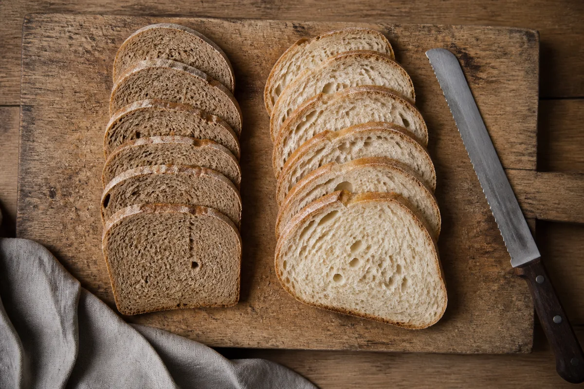 Tranches de pain de sarrasin et de pain d’épeautre disposées sur une planche de bois brut