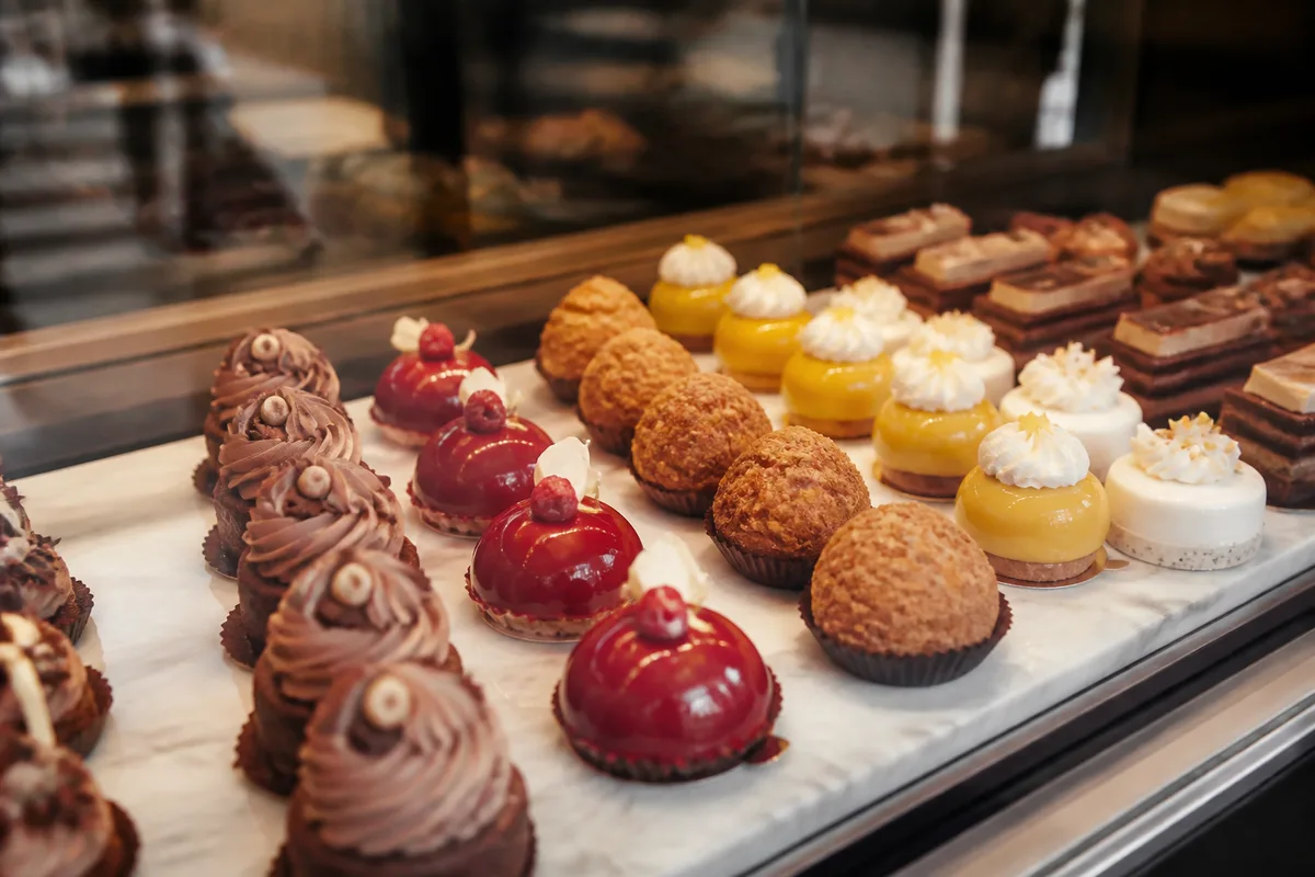 Vitrine de pâtisseries fines alignées avec régularité dans une boulangerie artisanale
